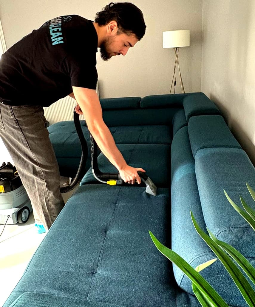 Technicien SafiClean nettoyant un canape a domicile